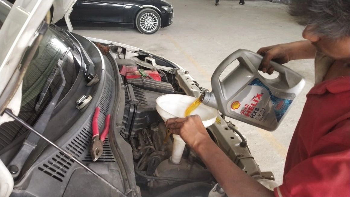 Mechanic checking engine oil levels during Mars Auto Care car service