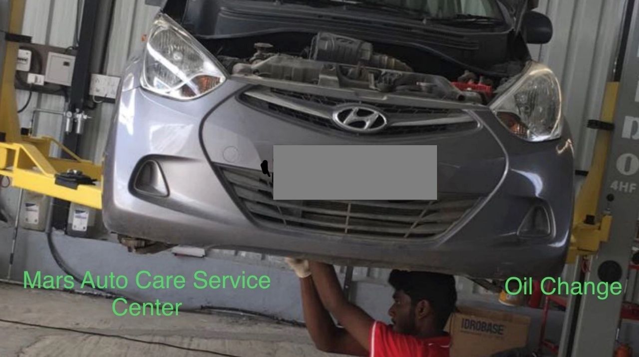 Mechanic checking engine oil levels during Mars Auto Care car service
